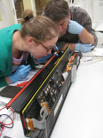 Two conservators examining a black box of electronics