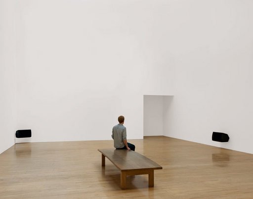 Installation view of Turner Prize winner Susan Philipszs Lowlands at Tate Britain October 2010 photograph of a white gallery with two audio speakers and a visitor sat on a bench 