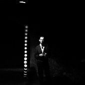 black and white high contrast photograph of the artist stood in front of his light installation.
