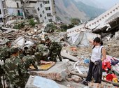 A woman stands amongst the debris of the earthquake in Sichuan Province South West China as rescue workers look for survivors May 2008