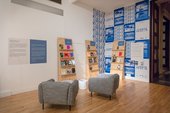 photograph showing two chairs in a gallery space in front of three bookcases