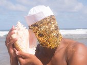 A person with a sequin mask and conch shell