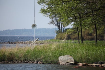 Picturesque scene of a lake and the green land which surrounds it with a speaker installed
