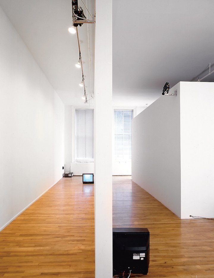 A TV monitor places on the floor in a white corridor